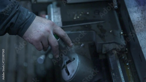 A worker's hand pulls a lever on a machine at the factory