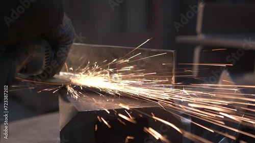 Sparks during pipe grinding at the factory by a worker