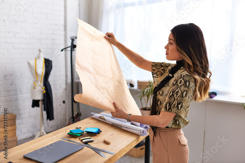 Φωτογραφία side view of young creative asian stylist looking at sewing patterns in personal