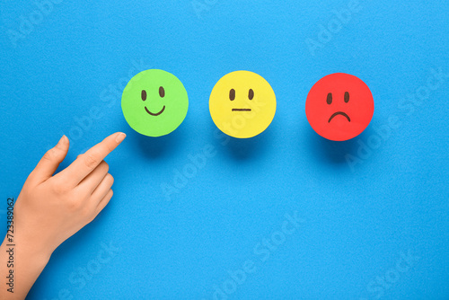 Woman pointing at rating smiles on blue background. Customer experience concept