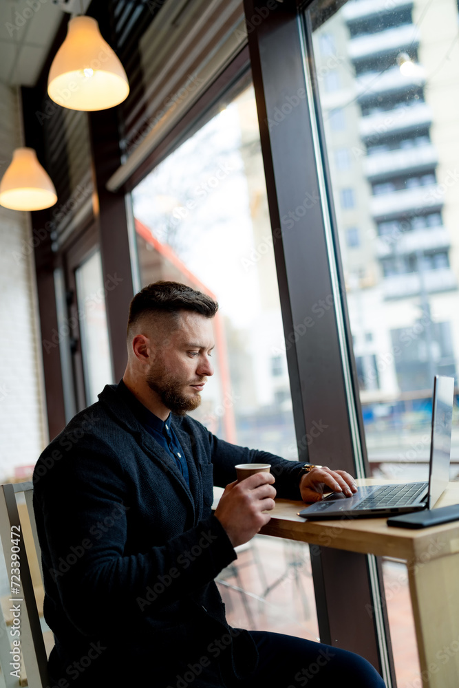 Young man works on laptop in cafe. Young man works on laptop in cafe.
