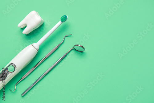 Electric toothbrush, dental tools and tooth model on green background. World Dentist Day