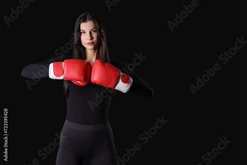 Sporty young woman in boxing gloves on black background © Pixel-Shot