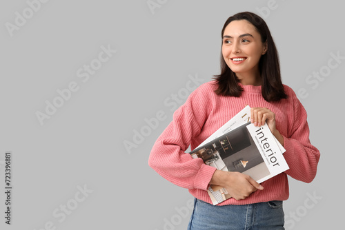 Beautiful woman with interior magazines on light background