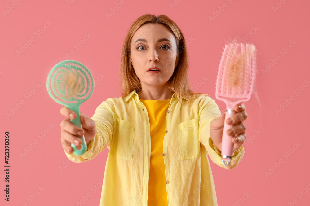 Worried mature woman with hair loss problem and brushes on pink background Worried mature woman with hair loss problem and brushes on pink background