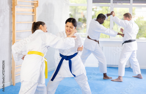 Adult women and young woman karatekas train karate in group in studio