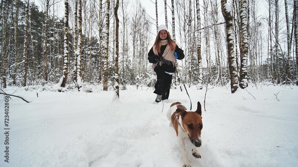 A girl and her Jack Russell Terrier dog are running through the woods. A girl and her Jack Russell Terrier dog are running through the woods.