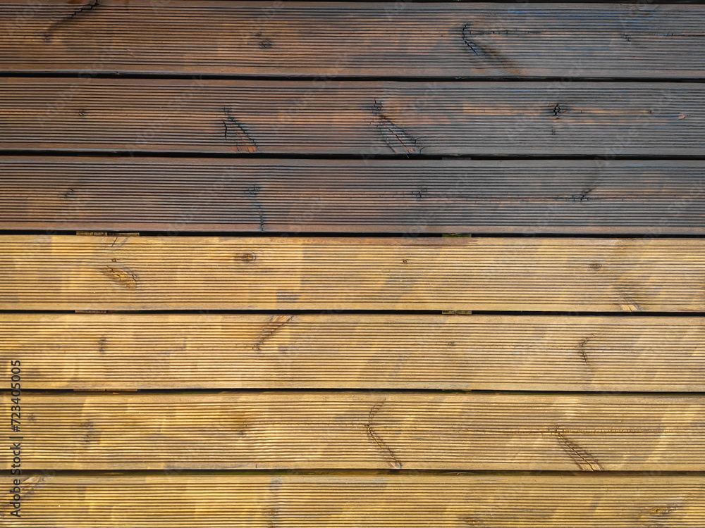 Partially painted and partly cleaned fluted wood terrace impregnated with oil. Top view of decking of wooden planks Partially painted and partly cleaned fluted wood terrace impregnated with oil. Top view of decking of wooden planks