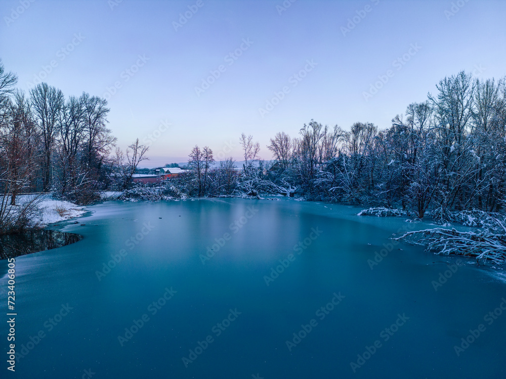 Drone view of forest covered in snow, with trees submerged in frozen lake near town of Samobor during beautiful sunset