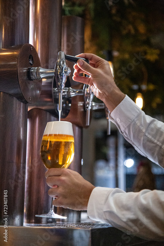Fotografia Camarero sirve una cerveza de un grifo en una barra de bar en una copa de crista