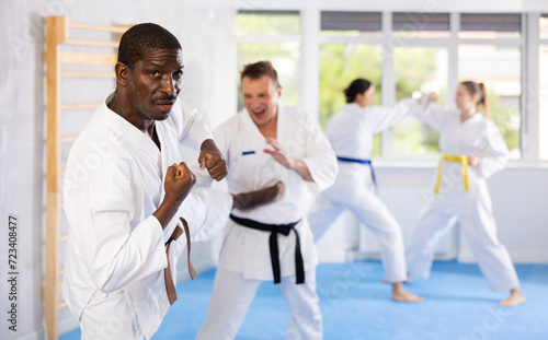 Multinational partners during martial arts karate class train to perform basic blows to opponent with hands and feet. Preparation of athletes for competitions