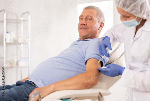 Retired man sitting at therapist appointment and undergoing procedure of mandatory annual vaccination against influenza, coronavirus