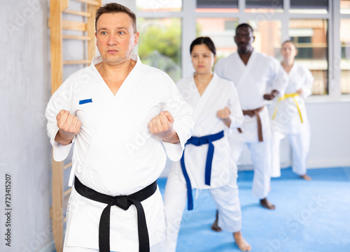 Kata karate teacher conducts classes and performs movements and fighting techniques together with cosmopolite students to prepare them for competitions.