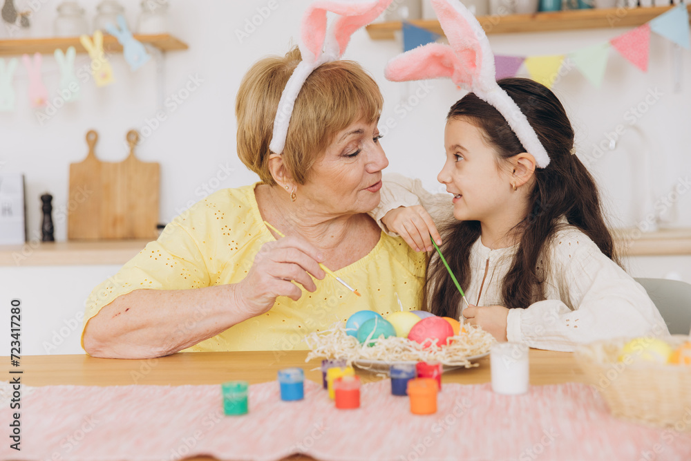 Fototapeta premium Happy easter! A grandmother and her granddaughter painting Easter eggs