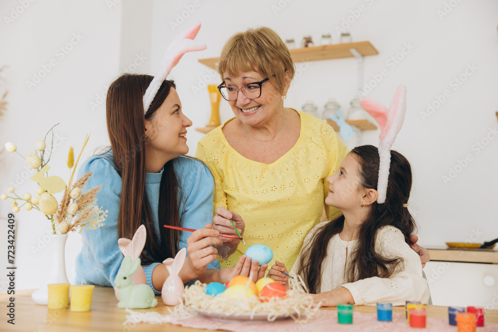 Three generations of women, happy mother with daughter and grandmother painting Easter eggs Three generations of women, happy mother with daughter and grandmother painting Easter eggs