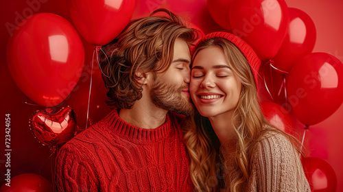 A romantic kissing couple holding red balloons on a red background
