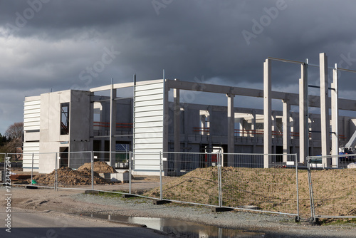 Baustelle mit Rohbau einer Gewerbehalle in einem Gewerbegebiet in Ahrensburg, Schleswig-Holstein. Dunkle Wolken über der Bauwirtschaft. April 2023.