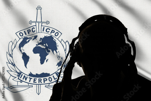 Dark silhouette of an interpol secret agent on the background of the flag of the secret service, eavesdropping on conversations, spy and special agent, Inscription in English, image of globe and sword photo