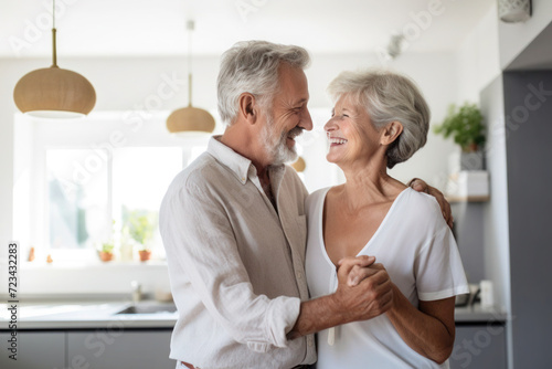 Caucasian married senior mature couple dancing in the kitchen