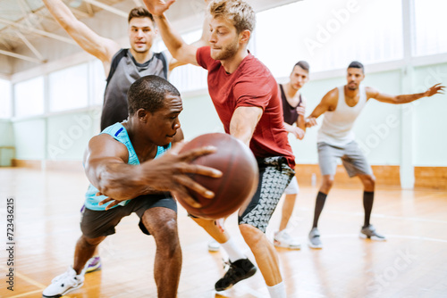 Diverse group of young men playing basketball in an indoor basketball gym photo