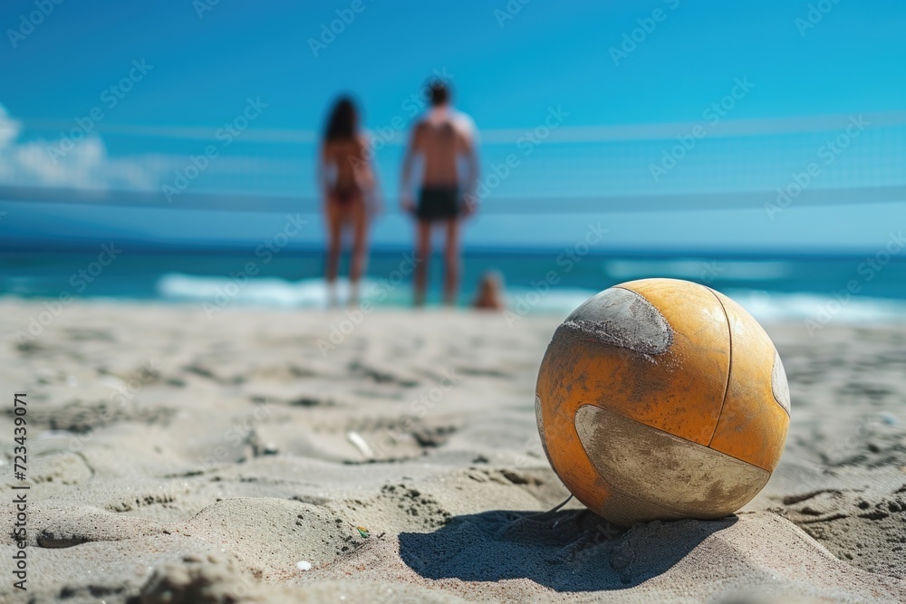 Volleyball frozen mid-air on a sunny beach with a couple by the net.