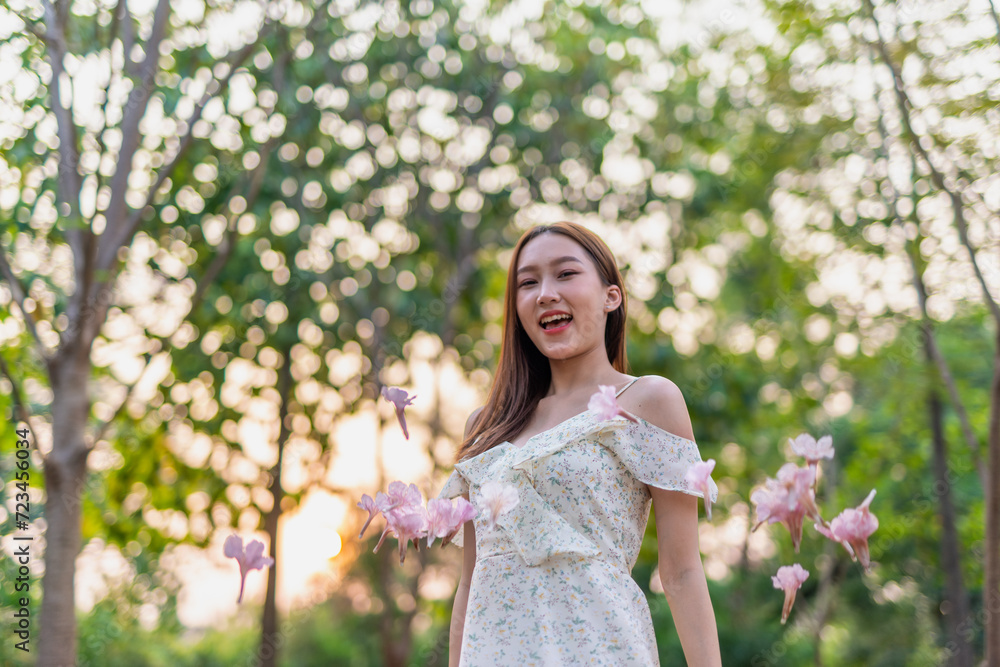 Young Asian beauty enjoys playing and posing with sakura flowers at a public park during sunset moments Young Asian beauty enjoys playing and posing with sakura flowers at a public park during sunset moments