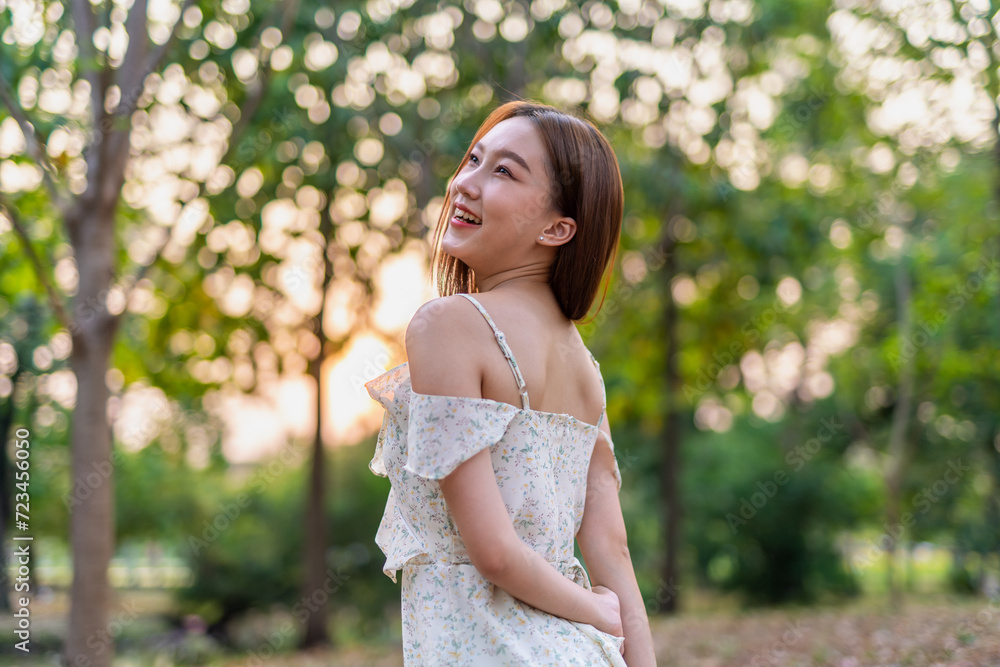 Young Asian beauty enjoys playing and posing with sakura flowers at a public park during sunset moments Young Asian beauty enjoys playing and posing with sakura flowers at a public park during sunset moments