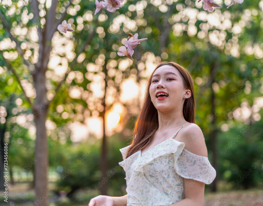 Beautiful young asian woman enjoying nature during sunset moments at a public park with lots of sakura flowers Beautiful young asian woman enjoying nature during sunset moments at a public park with lots of sakura flowers