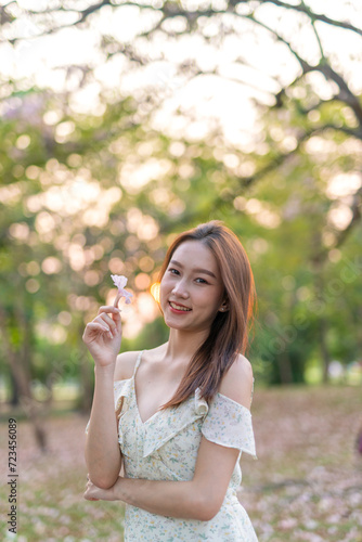 Beautiful young asian woman enjoying nature during sunset moments at a public park with lots of sakura flowers