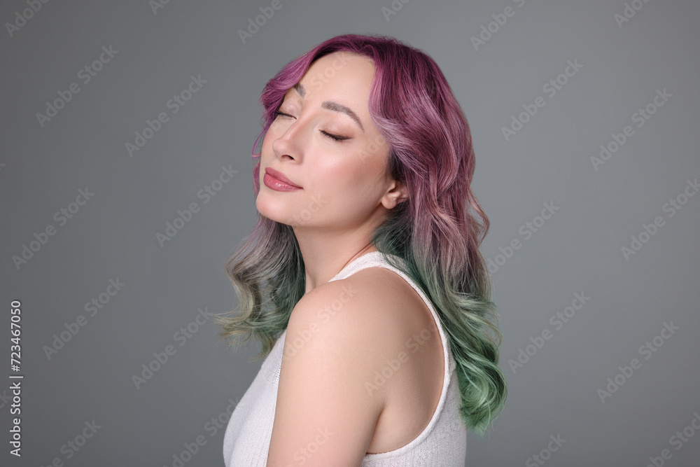 Naklejka premium Trendy hairstyle. Young woman with colorful dyed hair on grey background