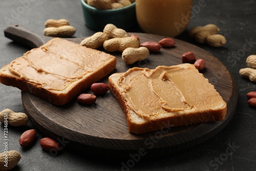 Tasty peanut butter sandwiches and peanuts on black table, closeup