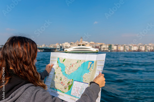 Happy teen girl, solo traveler, enjoying winter holidays. Concept of vacation. Attractive female tourist holding a paper map and exploring new city.