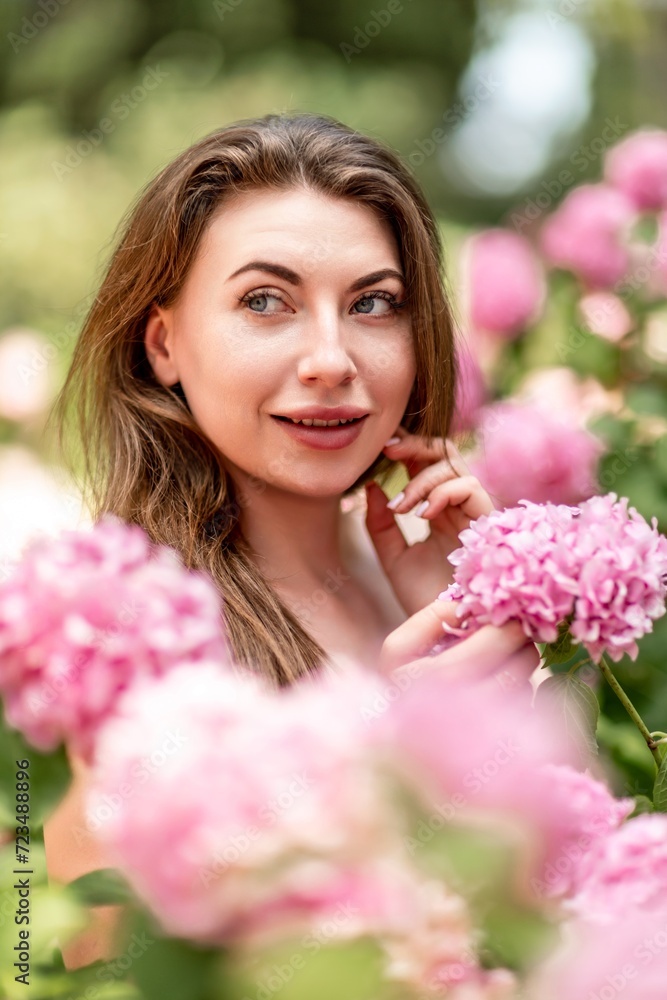 Hydrangeas Happy woman in pink dress amid hydrangeas. Large pink hydrangea caps surround woman. Sunny outdoor setting. Showcasing happy woman amid hydrangea bloom. Hydrangeas Happy woman in pink dress amid hydrangeas. Large pink hydrangea caps surround woman. Sunny outdoor setting. Showcasing happy woman amid hydrangea bloom.
