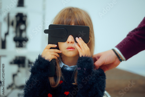Little Patient Girl Holding a Lorgnette Pinhole occluder for Consultation