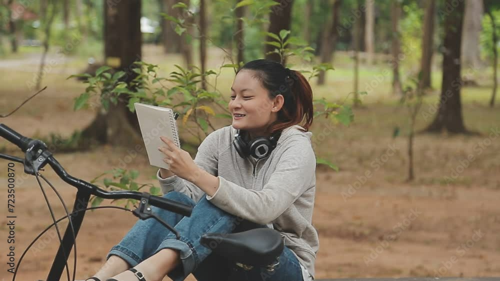 Chilling and relaxed young Asian woman in casual comfy clothes riding a bicycle on the bike lane in the park. hobby and exercise concept Chilling and relaxed young Asian woman in casual comfy clothes riding a bicycle on the bike lane in the park. hobby and exercise concept