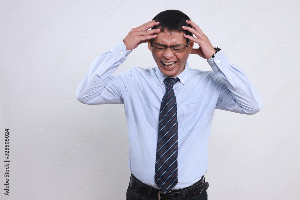 Stressed Asian businessman in shirt and tie holding his head and screaming suffering from headache or business failures Stressed Asian businessman in shirt and tie holding his head and screaming suffering from headache or business failures