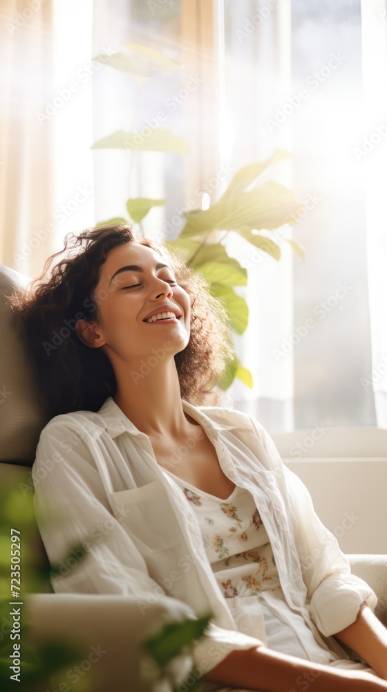 A Happy woman sitting in comfortable chair in home design, relaxing, breathing fresh air. A smiling young female tenant or a tenant relaxing in an armchair relieves negative emotions A Happy woman sitting in comfortable chair in home design, relaxing, breathing fresh air. A smiling young female tenant or a tenant relaxing in an armchair relieves negative emotions
