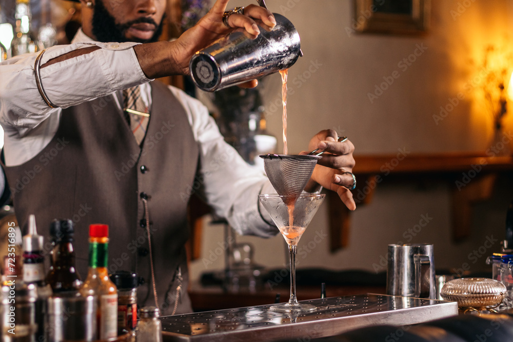 Black bartender preparing a cocktail in a traditional cocktail bar