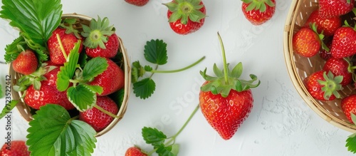 A white table displaying a strawberry sprout and a basket filled with fresh strawberries from above.