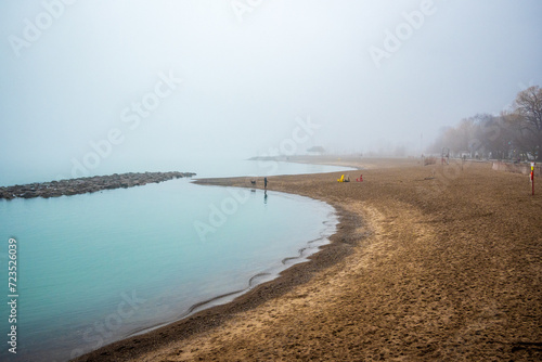 Canvas Print dog walkers on a foggy beach in winter shot kew beach toronto room for text