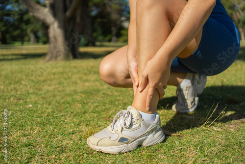 A woman holding onto her ankles after training. Outdoor exercise.