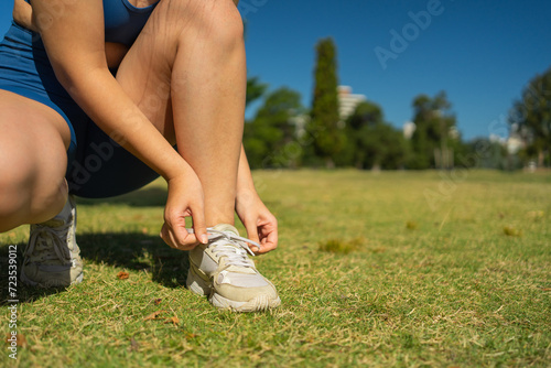 Woman runner tying shoelace, ready to run in the park. Outdoor exercise. © LVSN