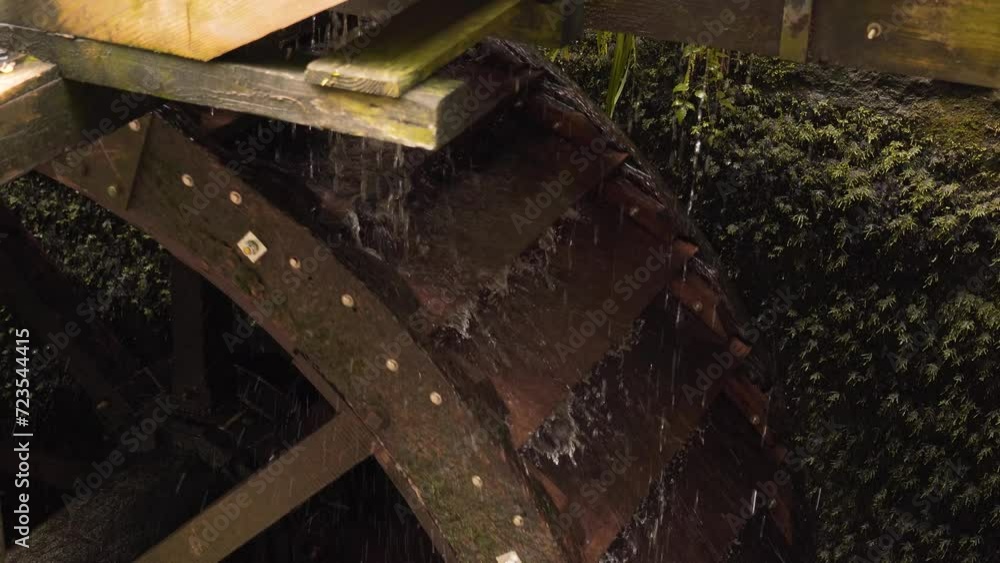 Close up on a section of a wooden water wheel from a water mill. Camera showing the water leaving the pockets of the wheel. Steady camera. Close up on a section of a wooden water wheel from a water mill. Camera showing the water leaving the pockets of the wheel. Steady camera.