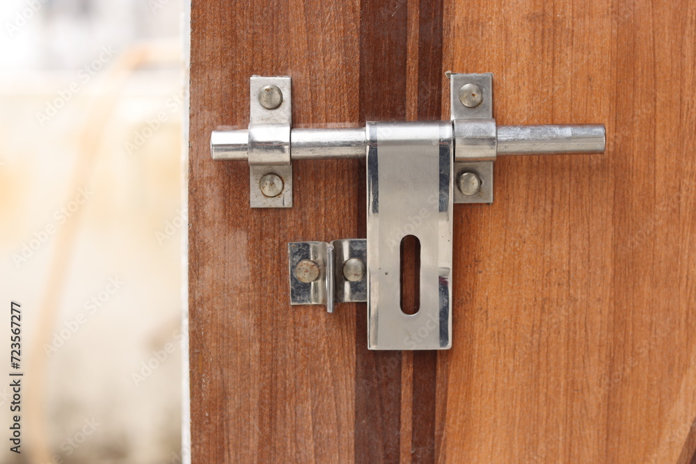 A close-up view of a weathered silver metal door latch on an aged wooden door, shining, old A close-up view of a weathered silver metal door latch on an aged wooden door, shining, old