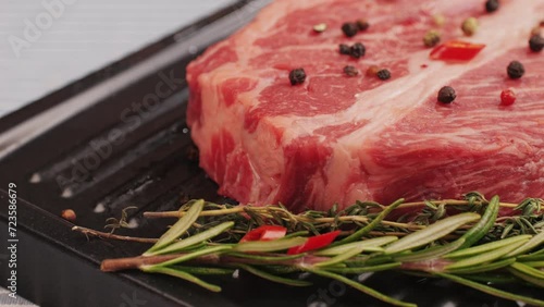 Fresh marbled beef with pepper, salt and rosemary close-up macro. Preparation to cook juicy steak on grill. Premium organic raw wagyu meat photo