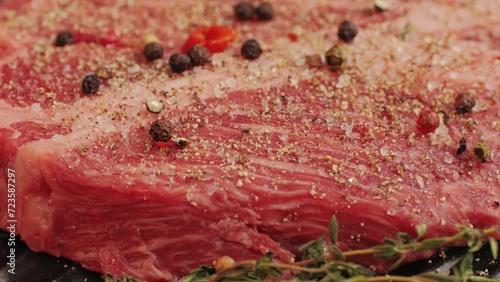 Fresh marbled beef with pepper, salt and rosemary close-up macro. Preparation to cook juicy steak on grill. Premium organic raw wagyu meat photo