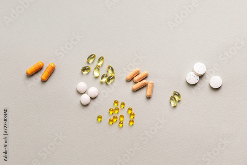 Groups of colored and different shaped pills, meds, capsules, tablets, vitamins, minerals and food supplements on light grey background top view.