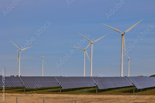 Solar panels and wind turbines under blue sky. Green energy concept.