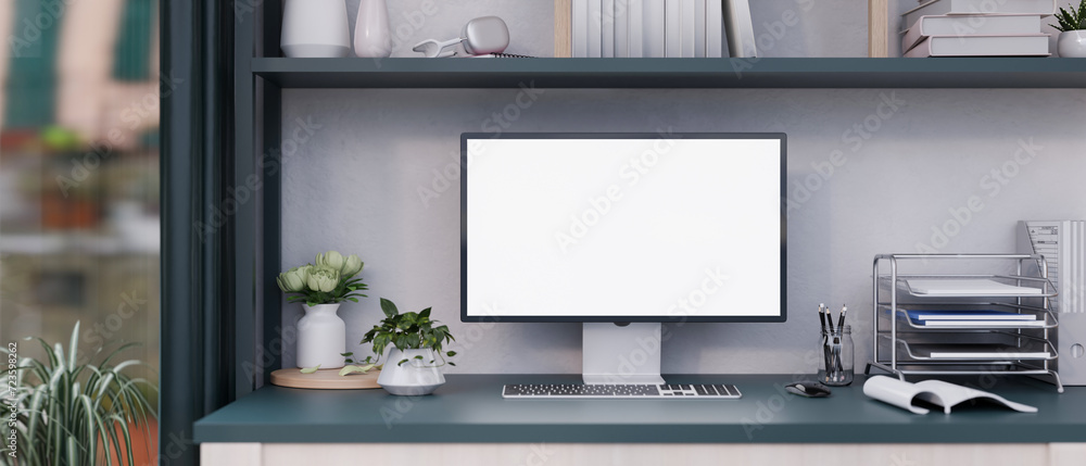 Front view of a white-screen computer mockup and office supplies on a desk in a modern office room. Front view of a white-screen computer mockup and office supplies on a desk in a modern office room.