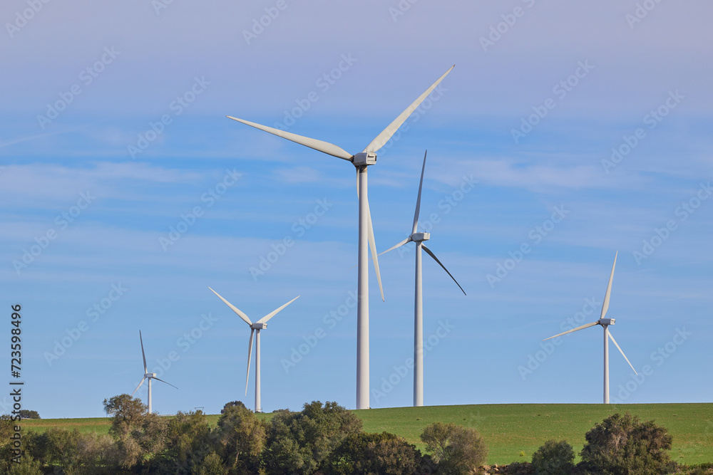 Fototapeta premium Wind turbines with landscape of agricultural fields under blue sky. Green energy concept.
